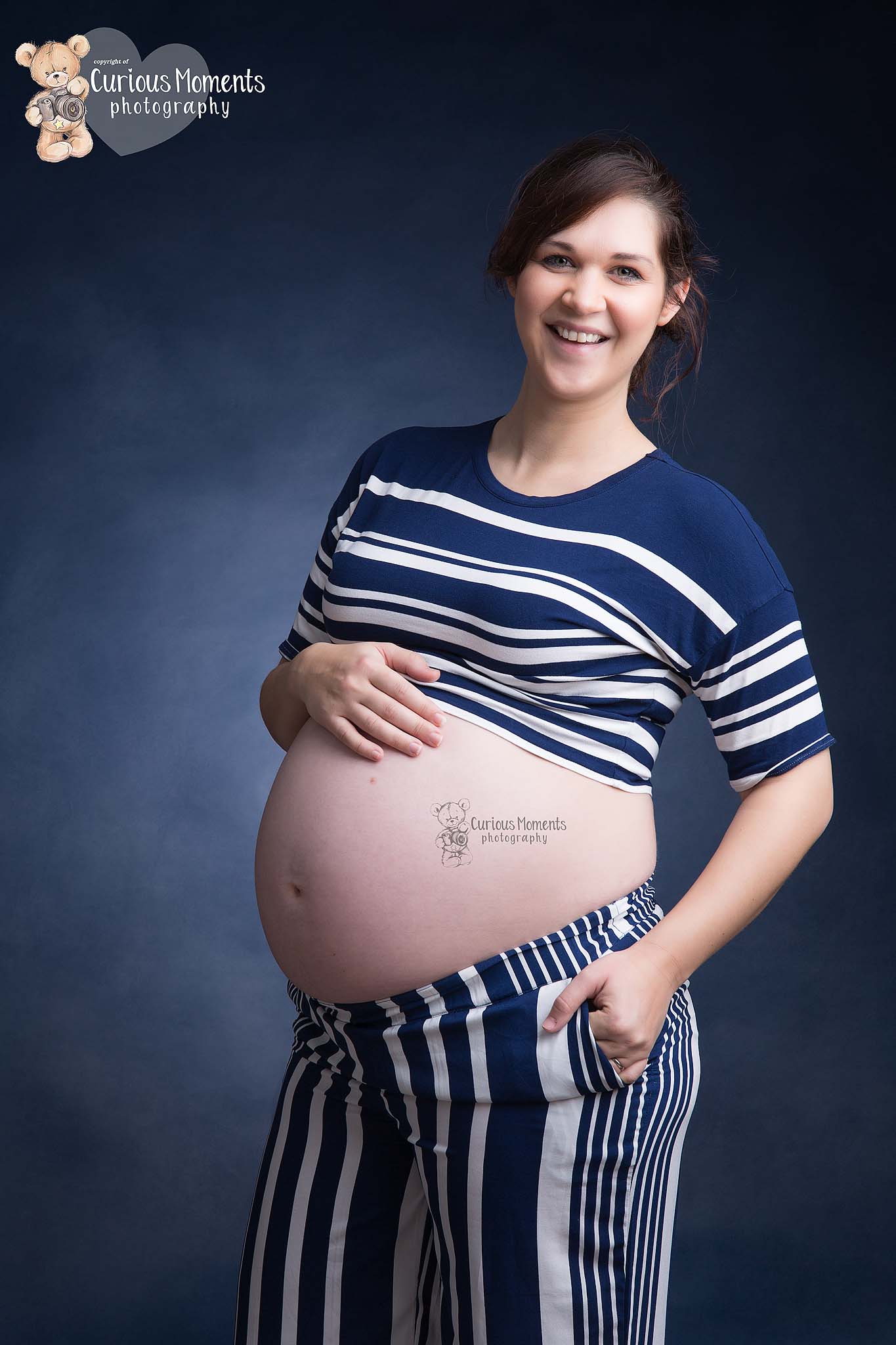Happy smiley fun photograph of pregnant woman wearing blue stripe top and trousers with Maternity Photographer Carmarthen